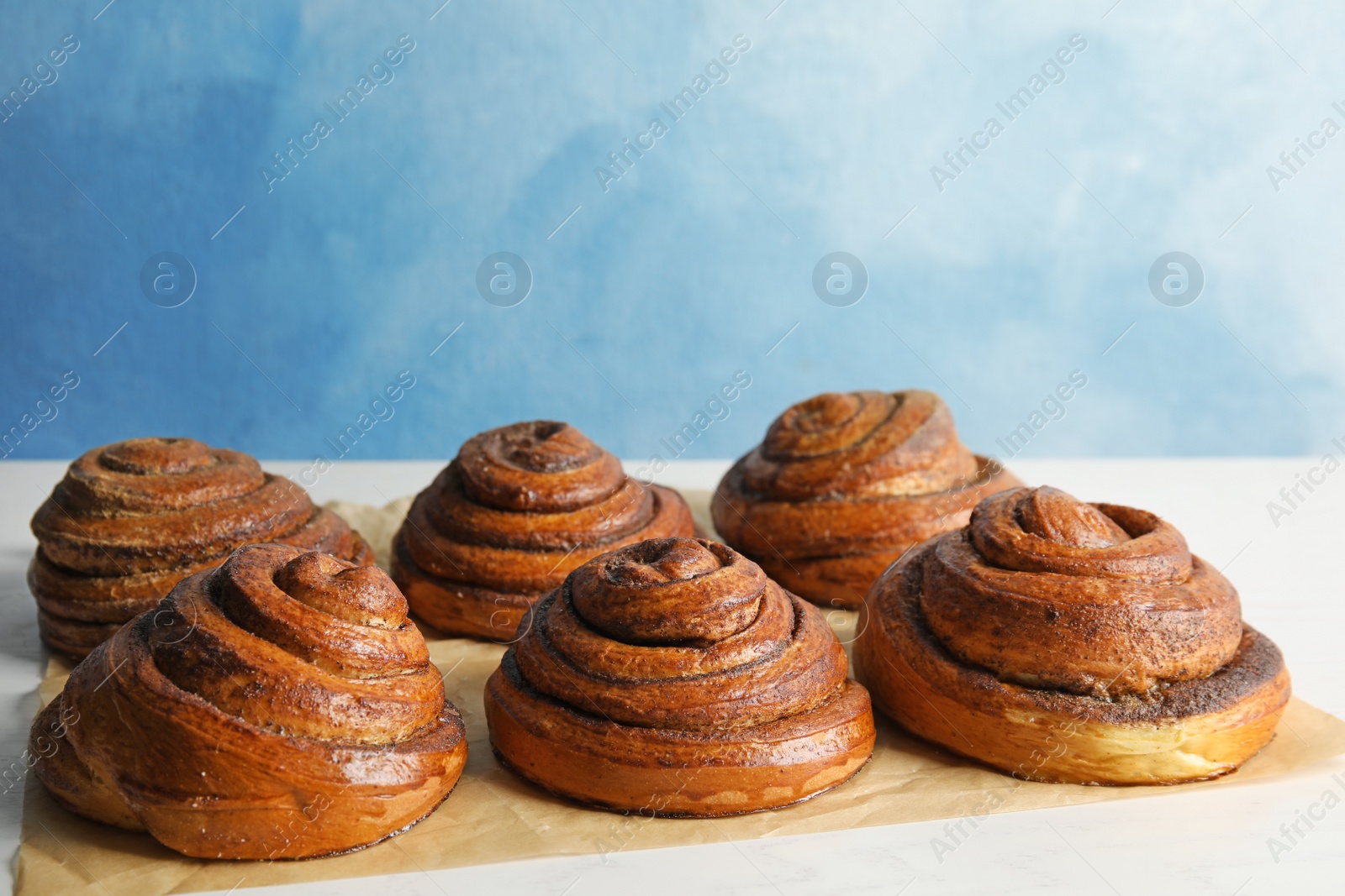 Photo of Parchment with freshly baked cinnamon rolls on table