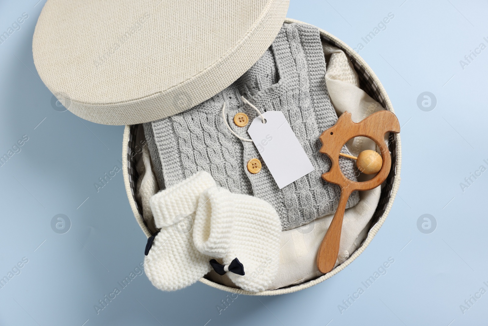 Photo of Different baby accessories and clothes in box on light blue background, top view