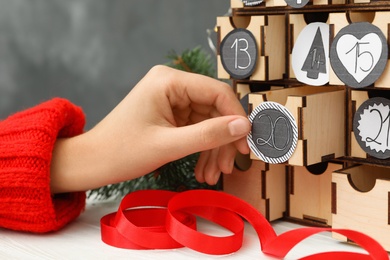 Woman making advent calendar at white wooden table, closeup