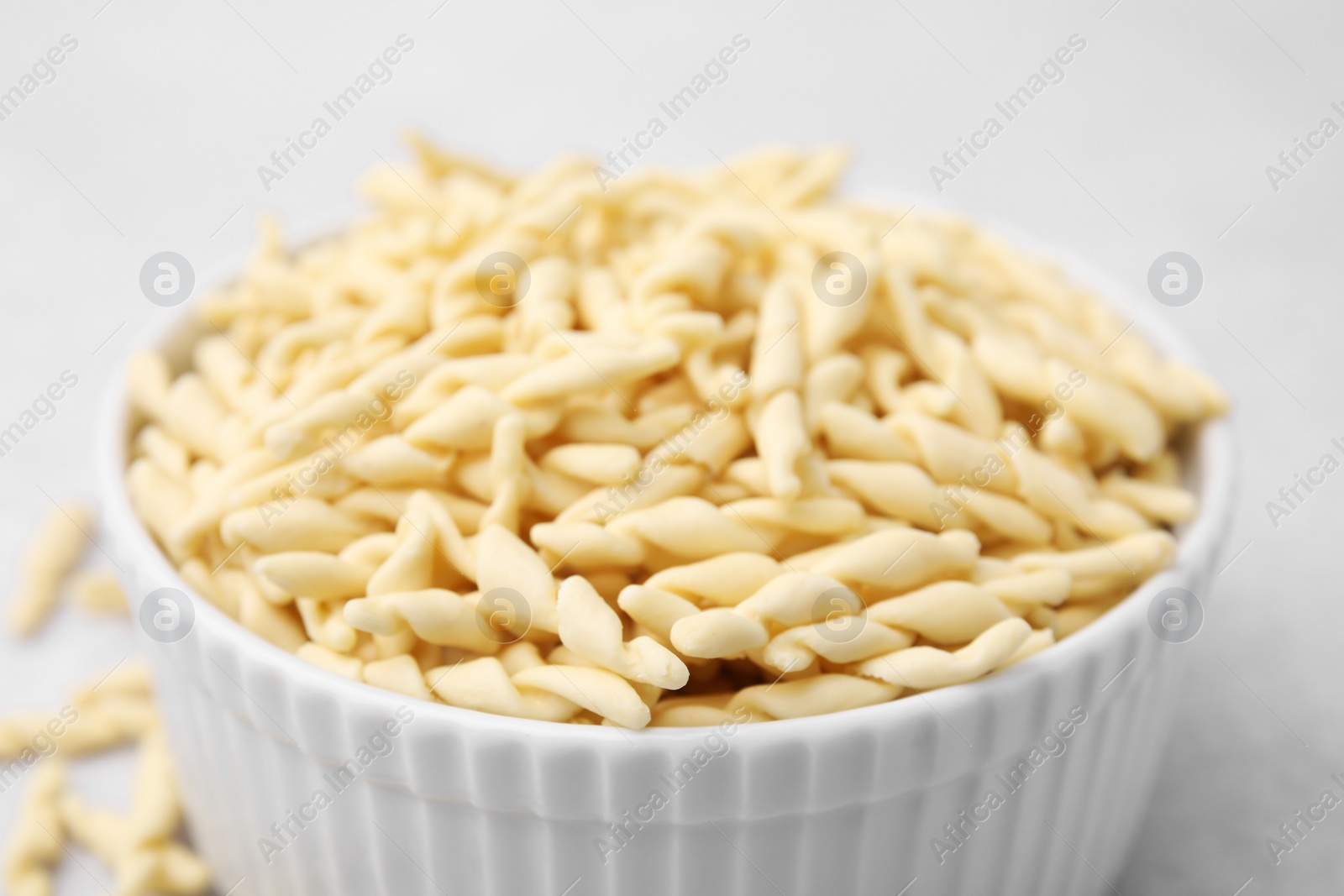 Photo of Uncooked trofie pasta in bowl on table, closeup