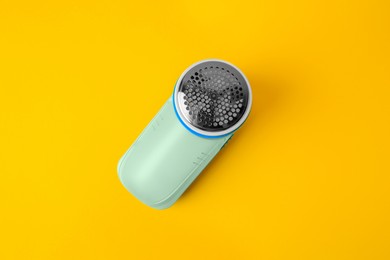 Photo of Modern fabric shaver on yellow background, top view
