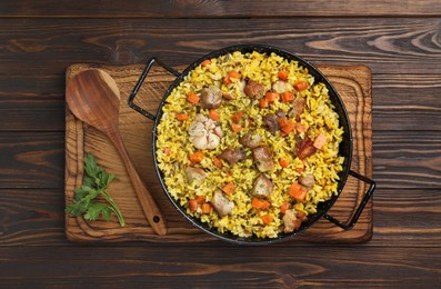 Photo of Delicious pilaf with meat, carrot and garlic served on wooden table, top view