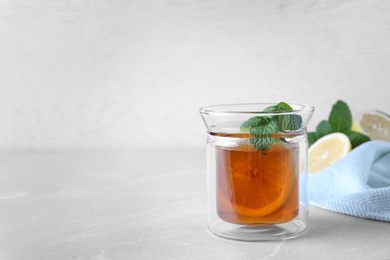 Photo of Hot tea with mint and lemon in glass on grey table. Space for text