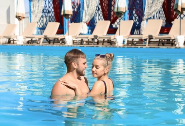 Photo of Happy young couple in swimming pool at resort