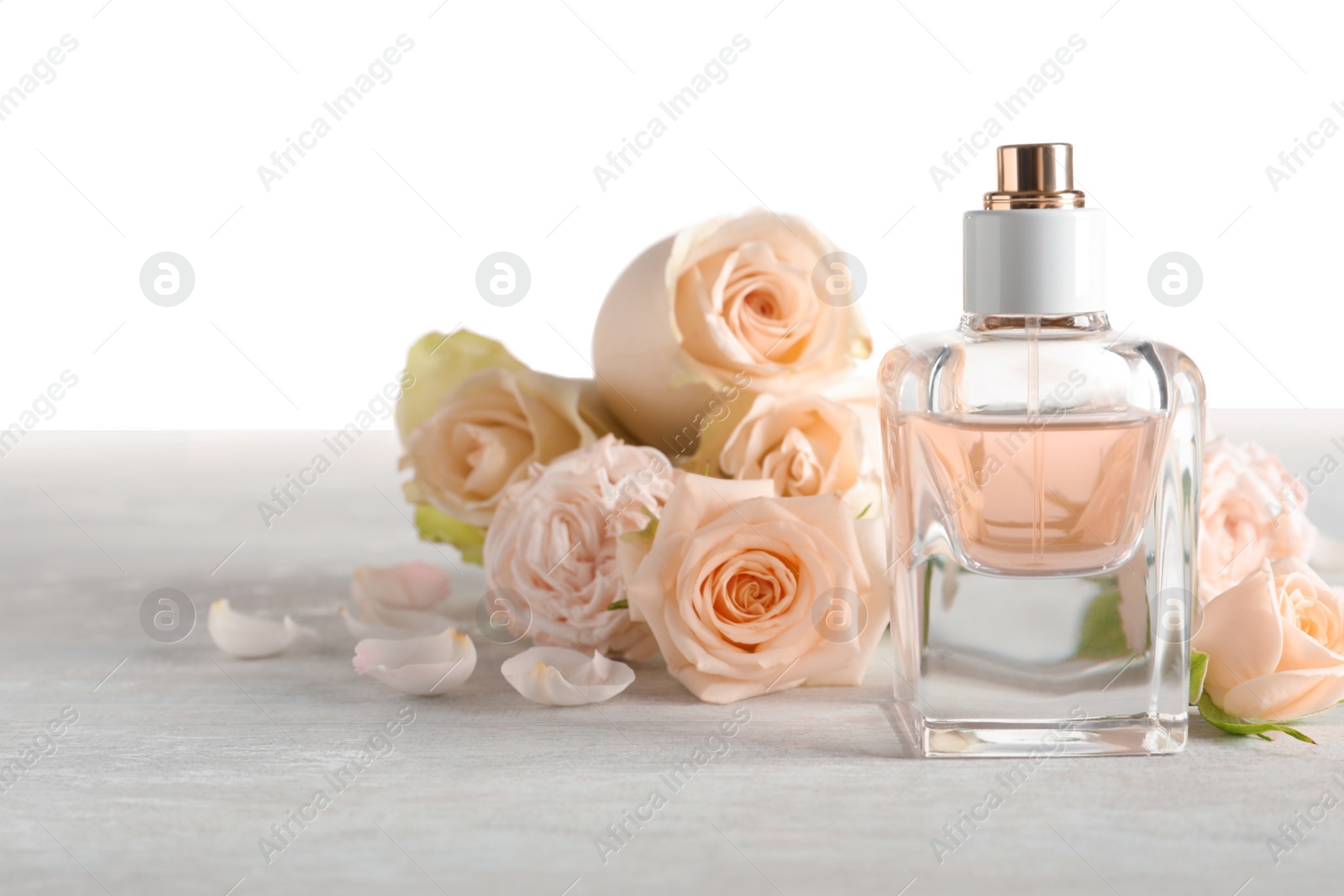 Photo of Elegant bottle of perfume and flowers on light background, space for text