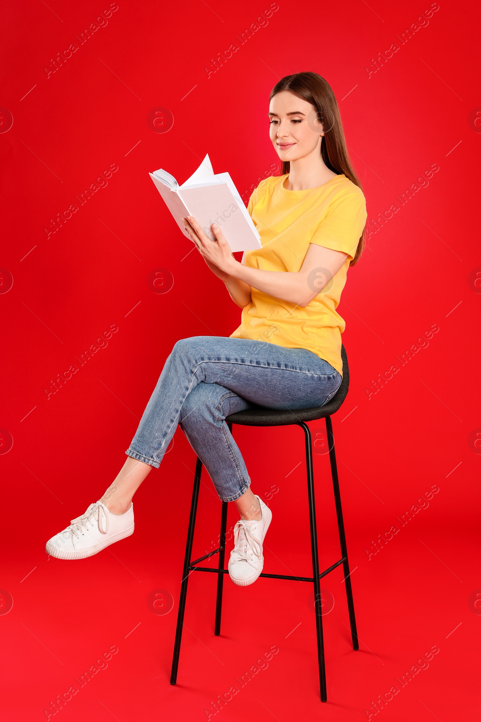 Photo of Young woman reading book on color background