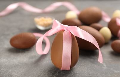 Sweet chocolate egg with pink bow on grey table