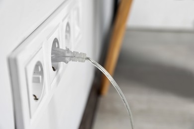 Photo of Power socket and plug on wall indoors, closeup