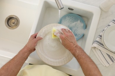 Photo of Man washing plate above sink, top view