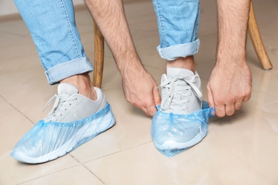 Man putting on blue shoe covers, closeup