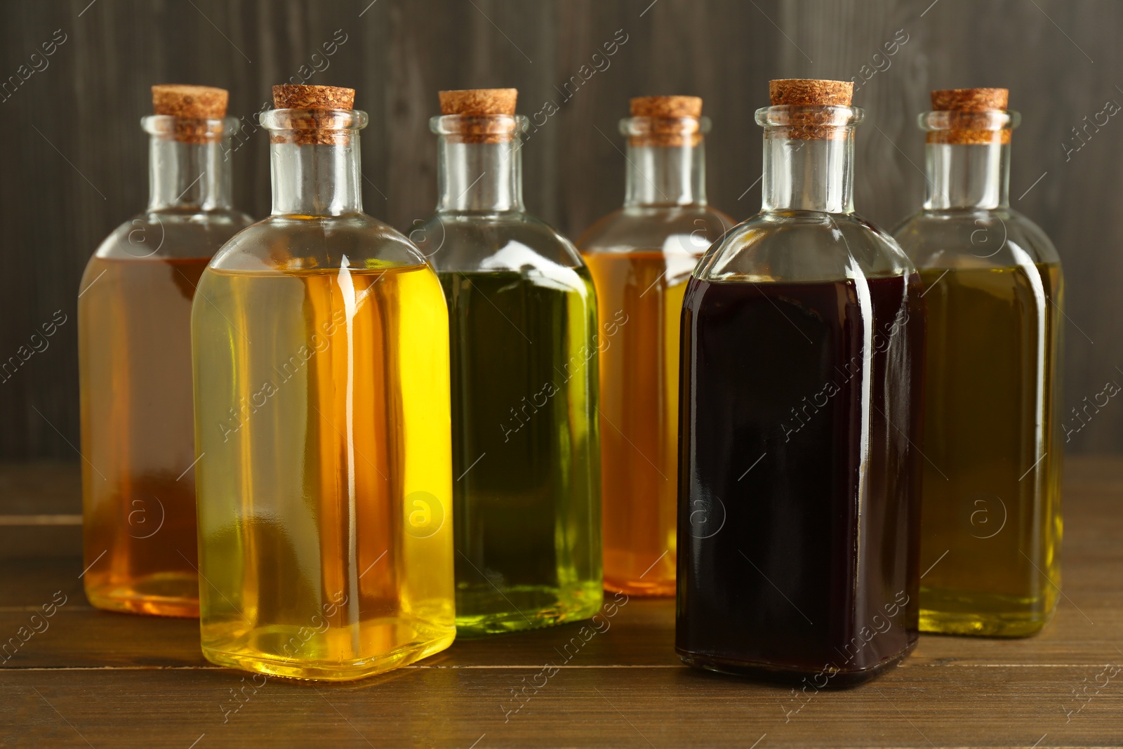 Photo of Vegetable fats. Different oils in glass bottles on wooden table