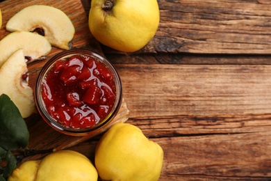 Photo of Delicious quince jam and fruits on wooden table, flat lay. Space for text