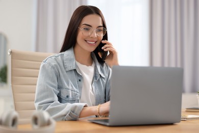 Young woman talking on smartphone during webinar at table in room