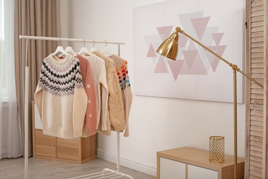 Photo of Wardrobe rack with stylish warm clothes indoors
