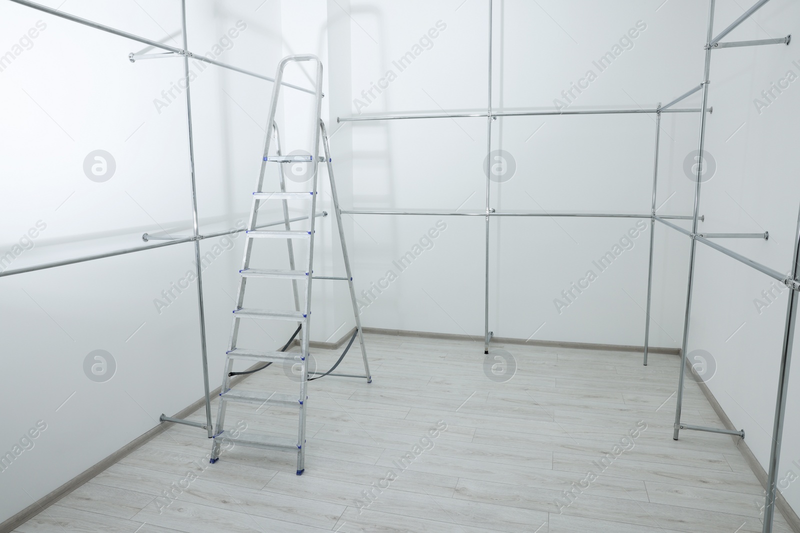 Photo of Ladder and metal pipes in empty renovated room