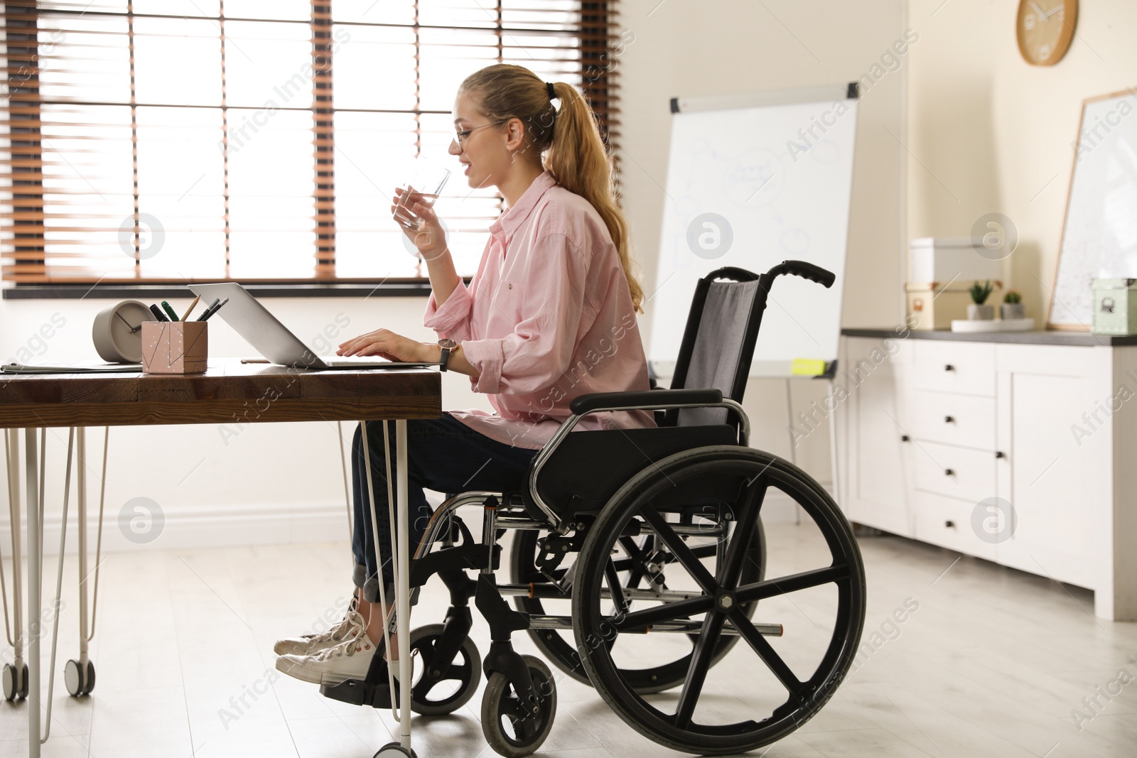 Photo of Woman in wheelchair drinking water at workplace