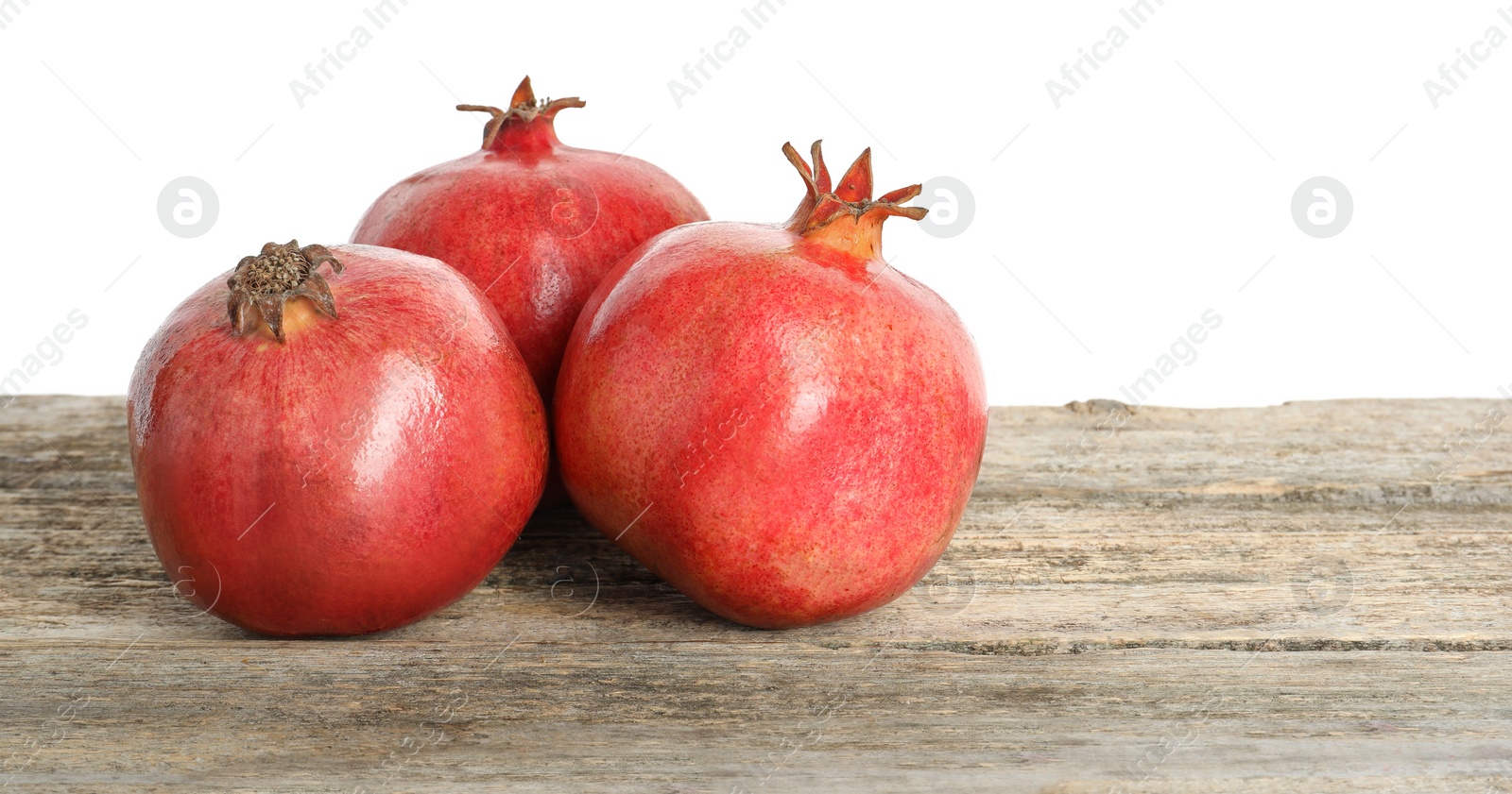 Photo of Fresh pomegranates on wooden table against white background, space for text