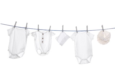 Photo of Different baby clothes drying on laundry line against white background