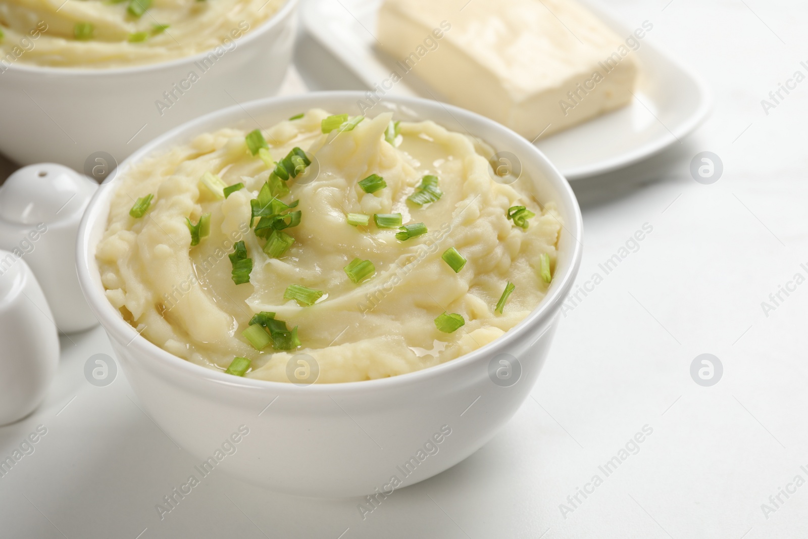 Photo of Bowls of delicious mashed potato with green onion on white table