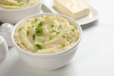 Photo of Bowls of delicious mashed potato with green onion on white table