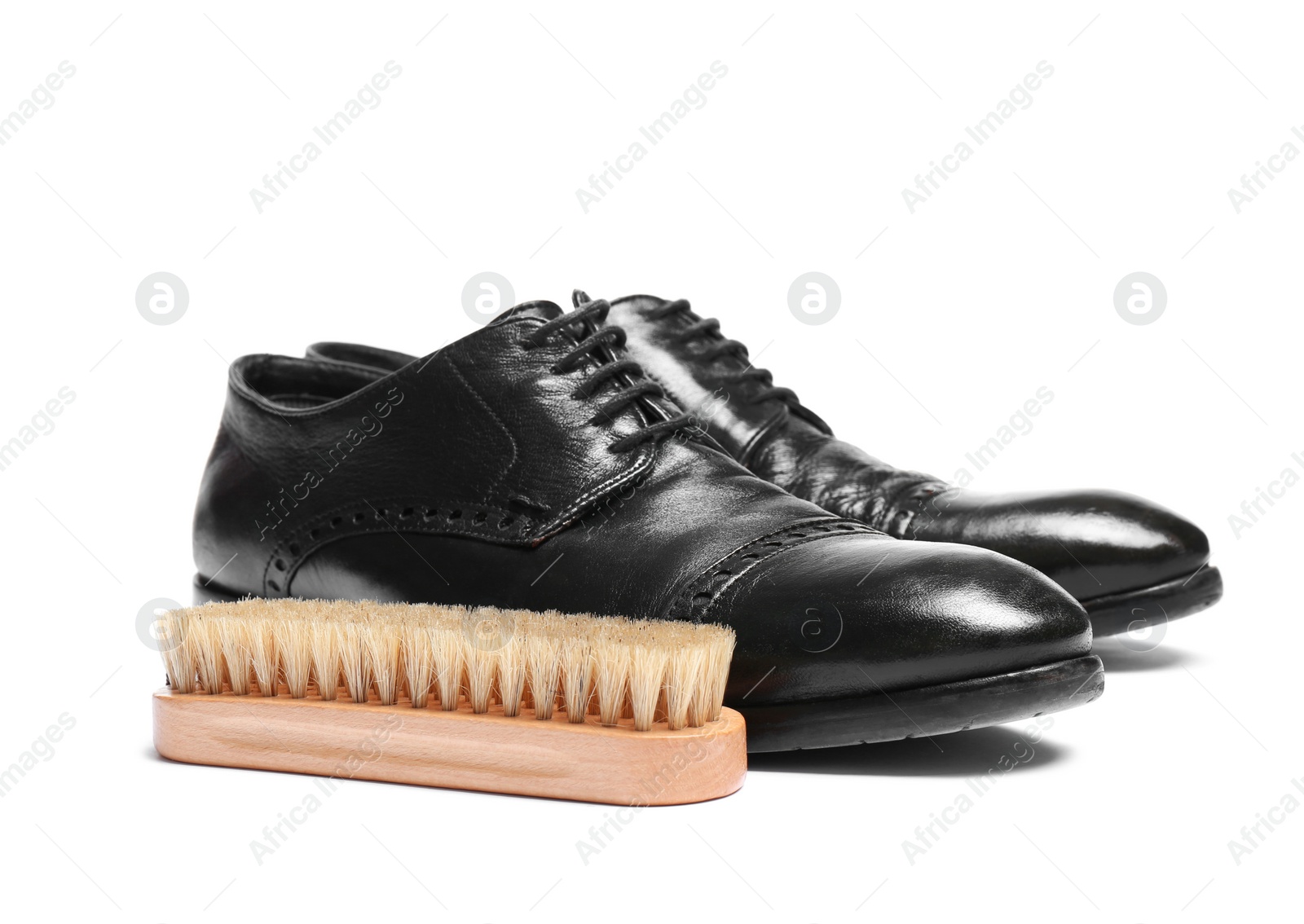 Photo of Stylish men's shoes and cleaning brush on white background