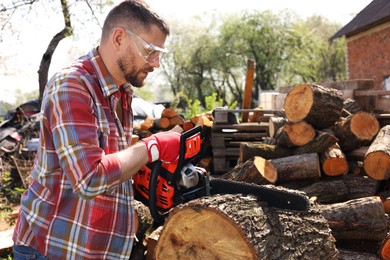 Man sawing wooden log on sunny day