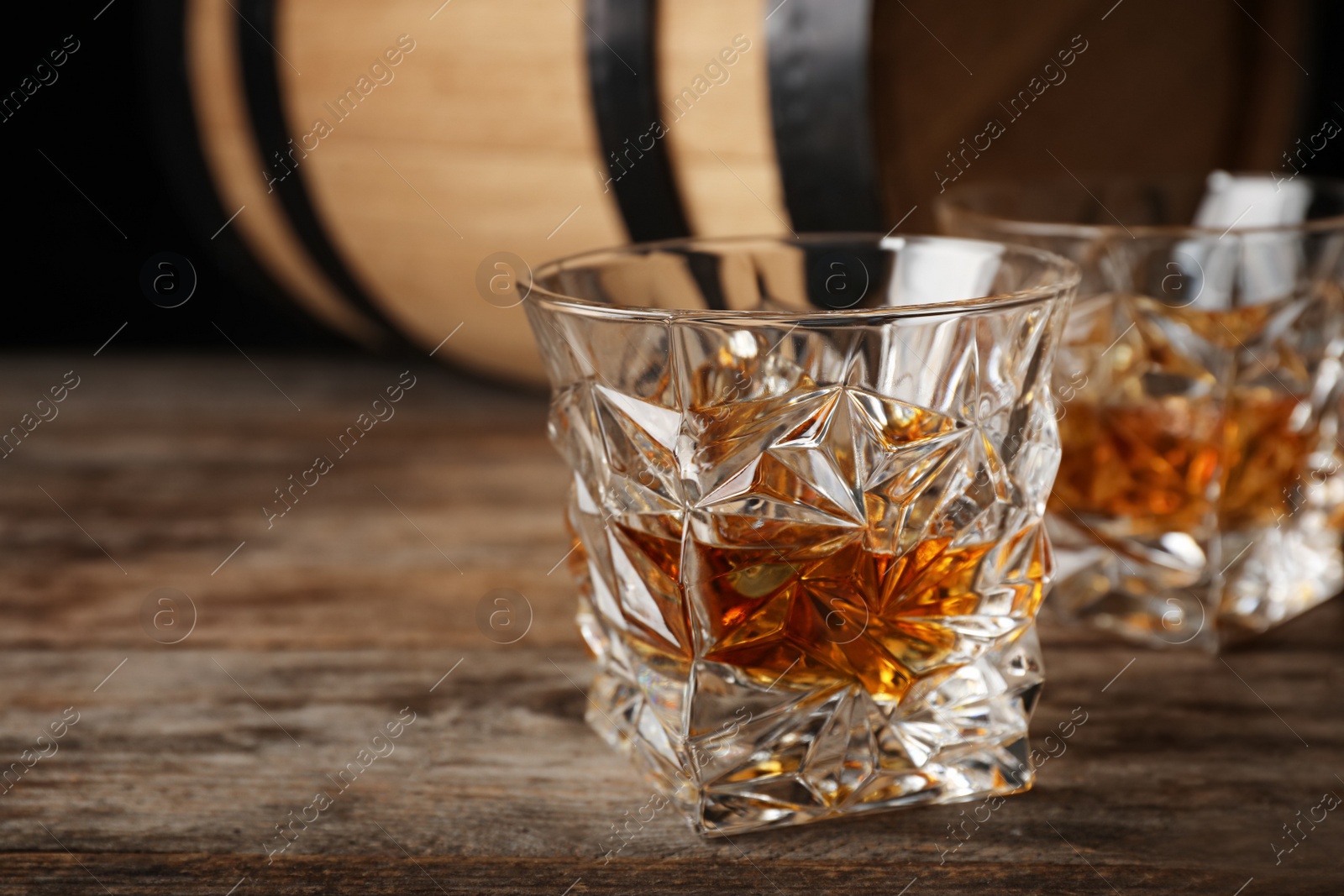 Photo of Golden whiskey in glass with ice cubes on wooden table. Space for text