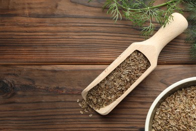 Photo of Scoop of dry seeds, bowl and fresh dill on wooden table, flat lay. Space for text