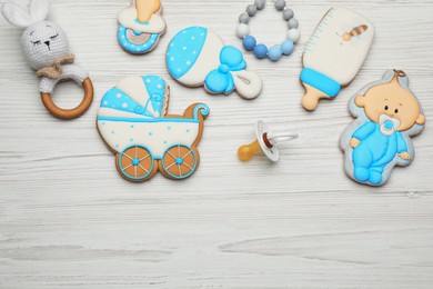 Photo of Cute tasty cookies of different shapes, pacifier and space for text on white wooden table, flat lay. Baby shower party