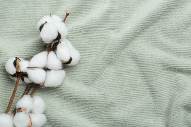 Photo of Cotton flowers on soft towels, top view. Space for text