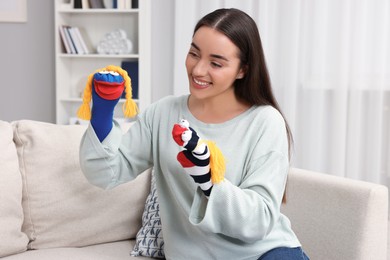 Happy woman performing puppet show on sofa at home