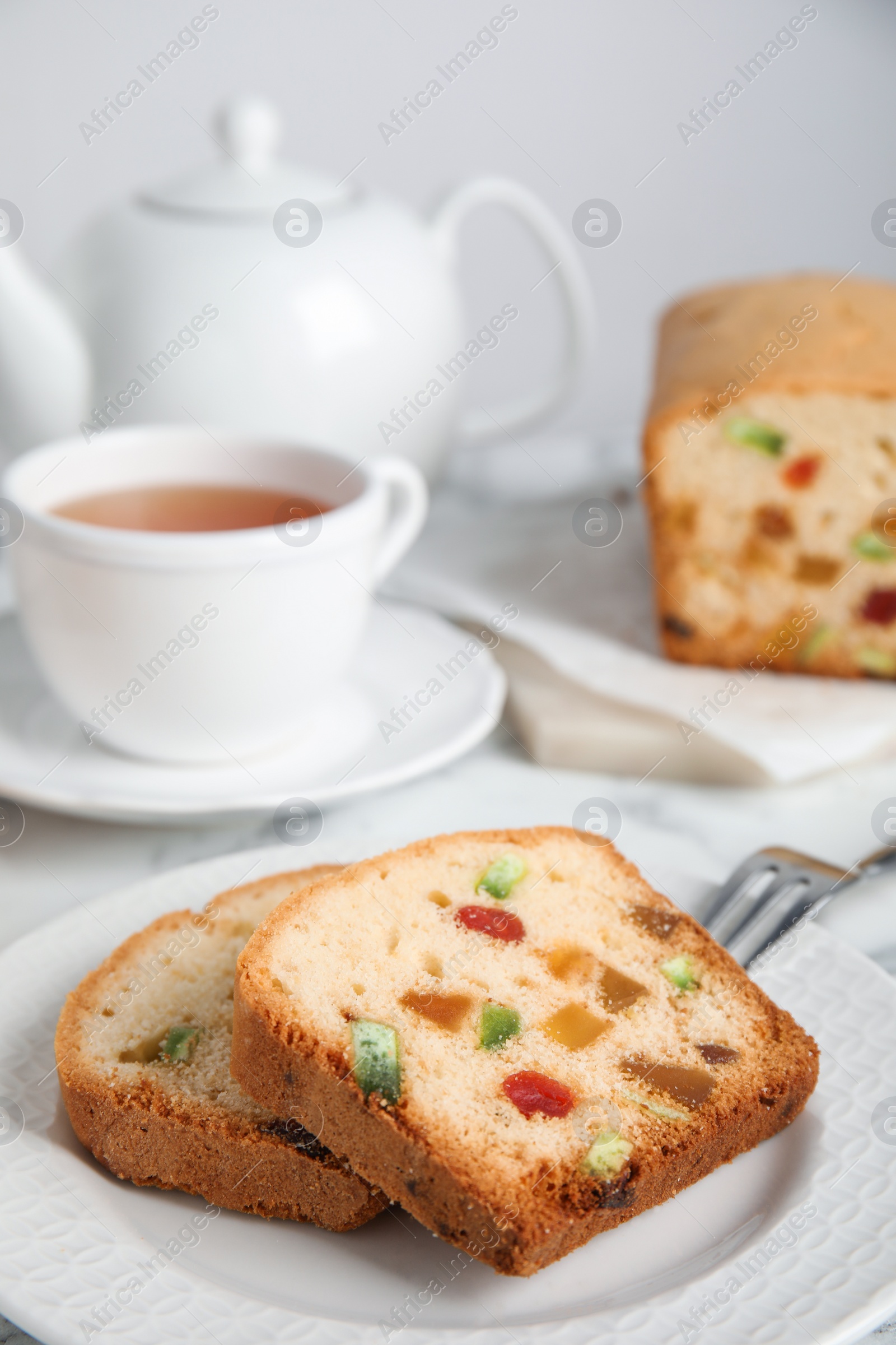 Photo of Delicious cake with candied fruits and tea on table, closeup