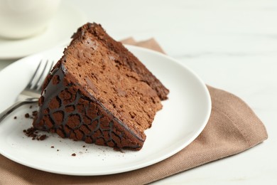 Piece of delicious chocolate truffle cake and fork on white table, closeup