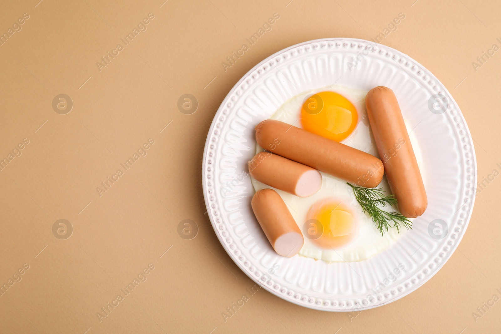 Photo of Delicious boiled sausages, fried eggs and dill on beige background, top view. Space for text