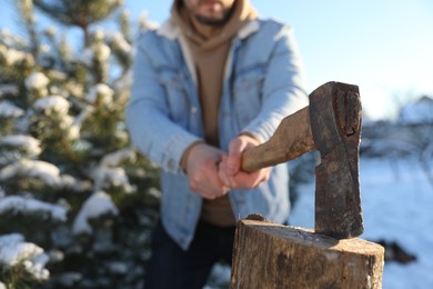 Man chopping wood with axe outdoors on winter day, closeup