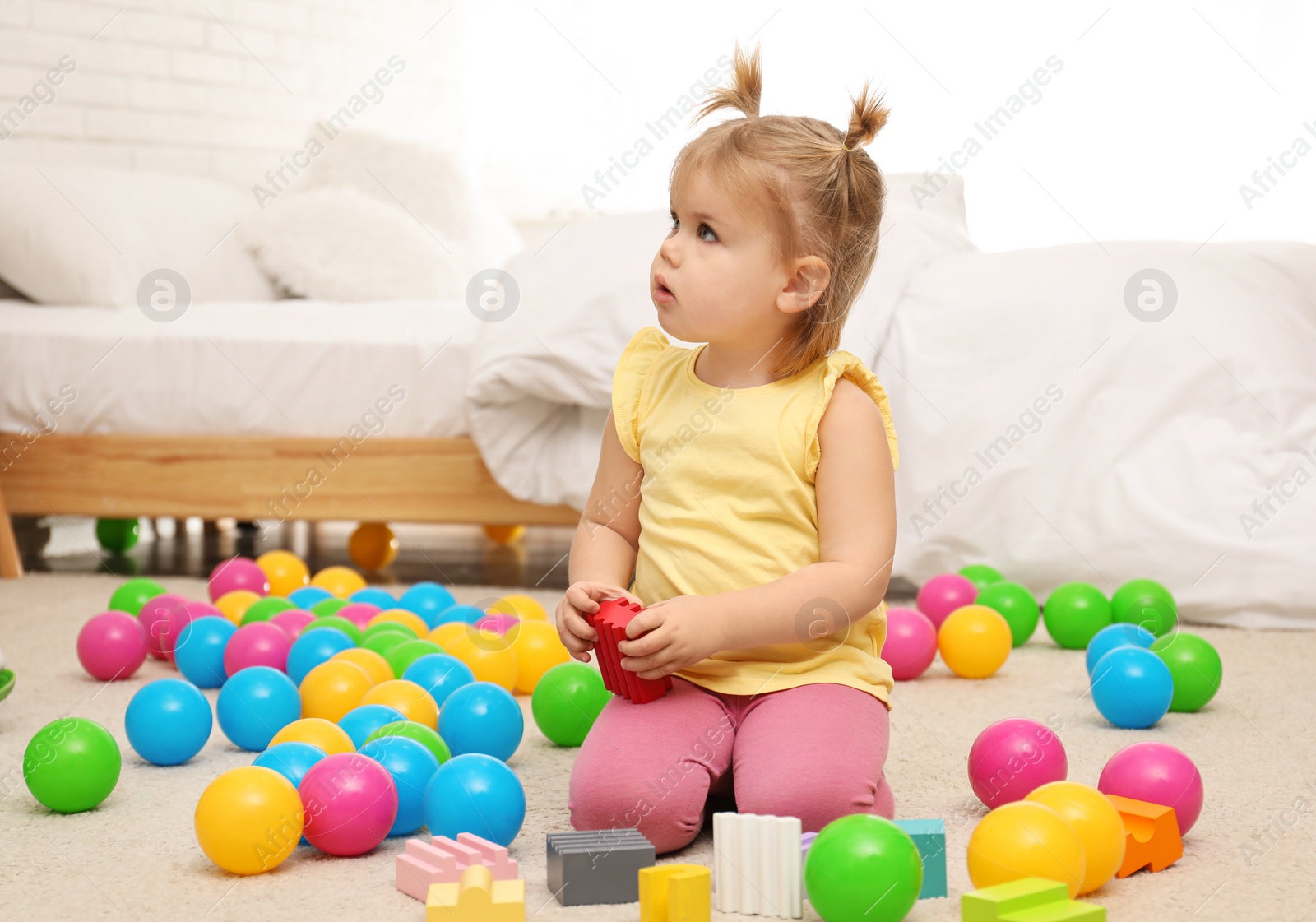 Photo of Cute little child playing with toys on floor at home