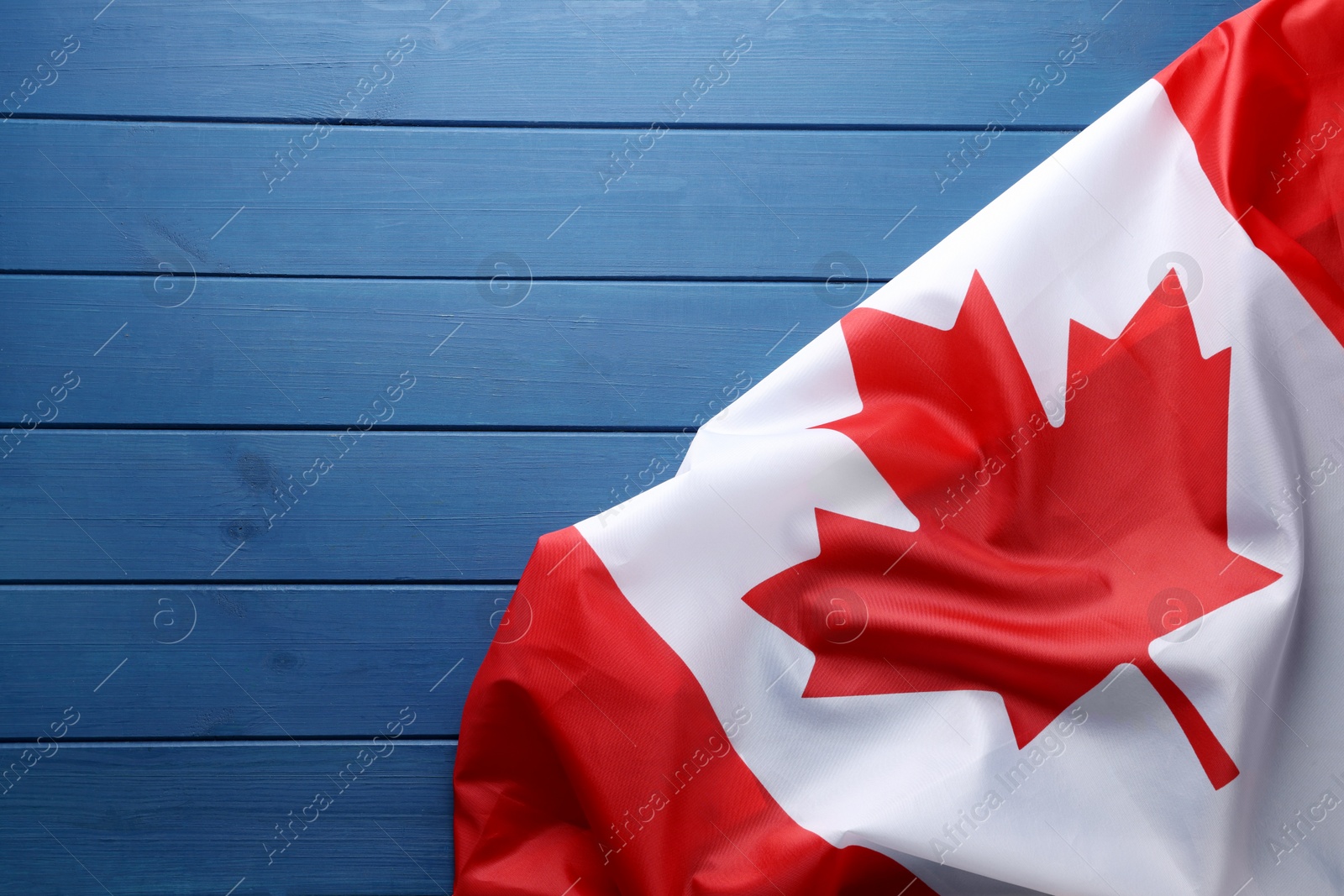 Photo of Flag of Canada on blue wooden table, top view. Space for text