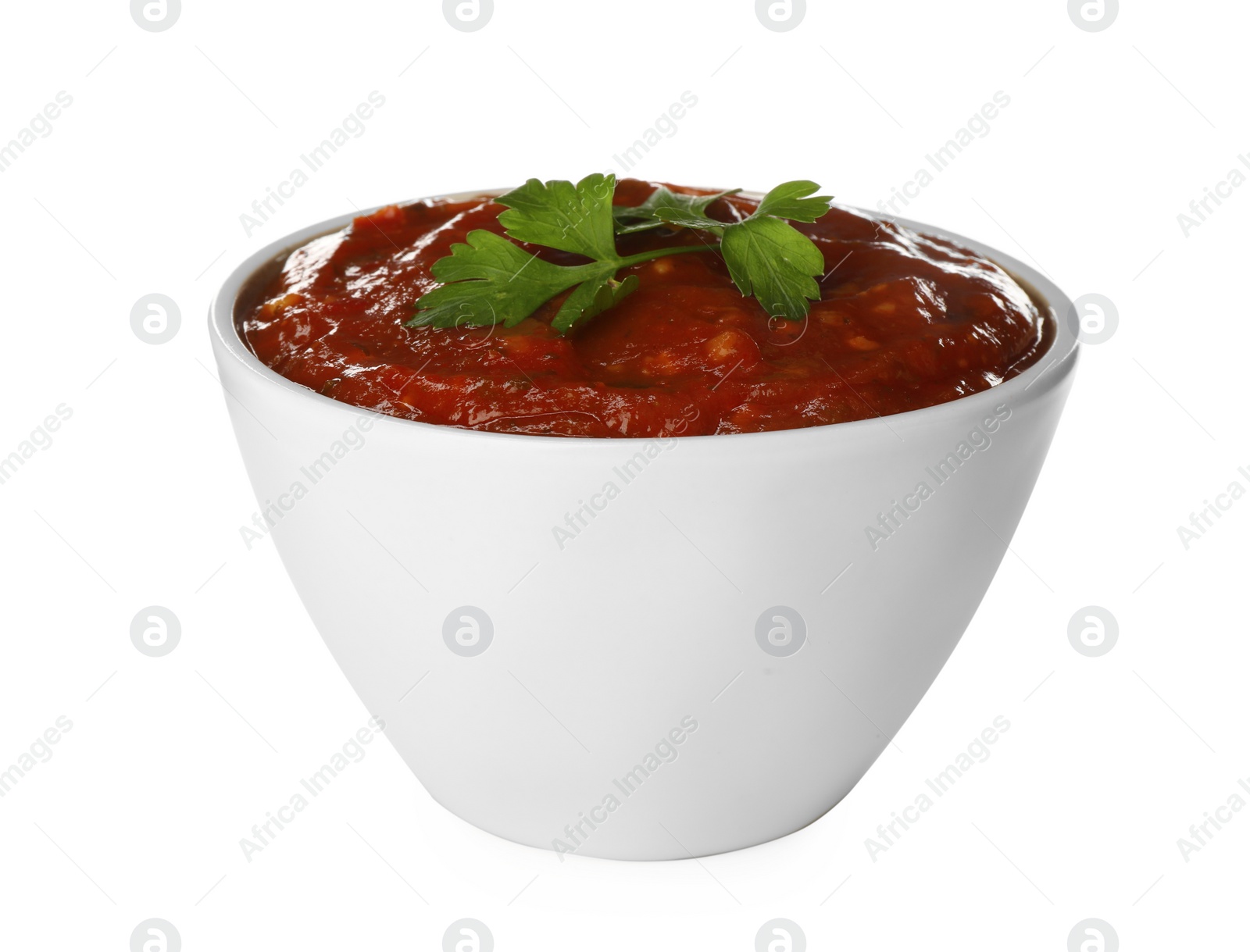 Photo of Delicious adjika sauce and parsley in bowl isolated on white