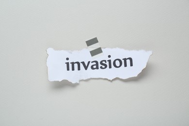 Photo of Paper with word Invasion on beige background, top view