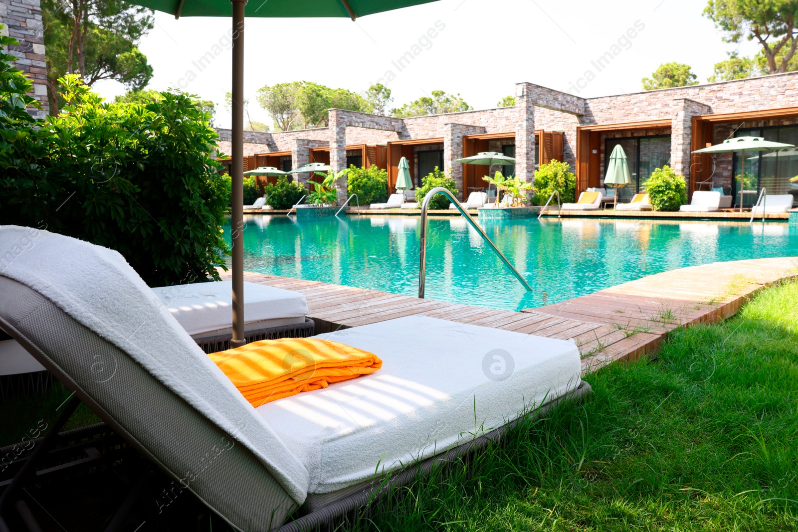 Photo of Sunbeds near outdoor swimming pool at luxury resort