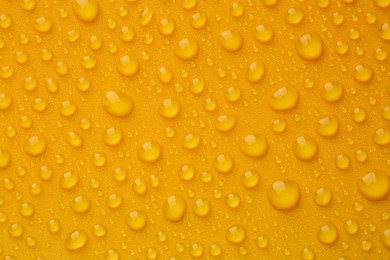 Water drops on orange background, top view