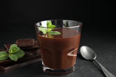 Photo of Glass of delicious hot chocolate with mint on dark grey table