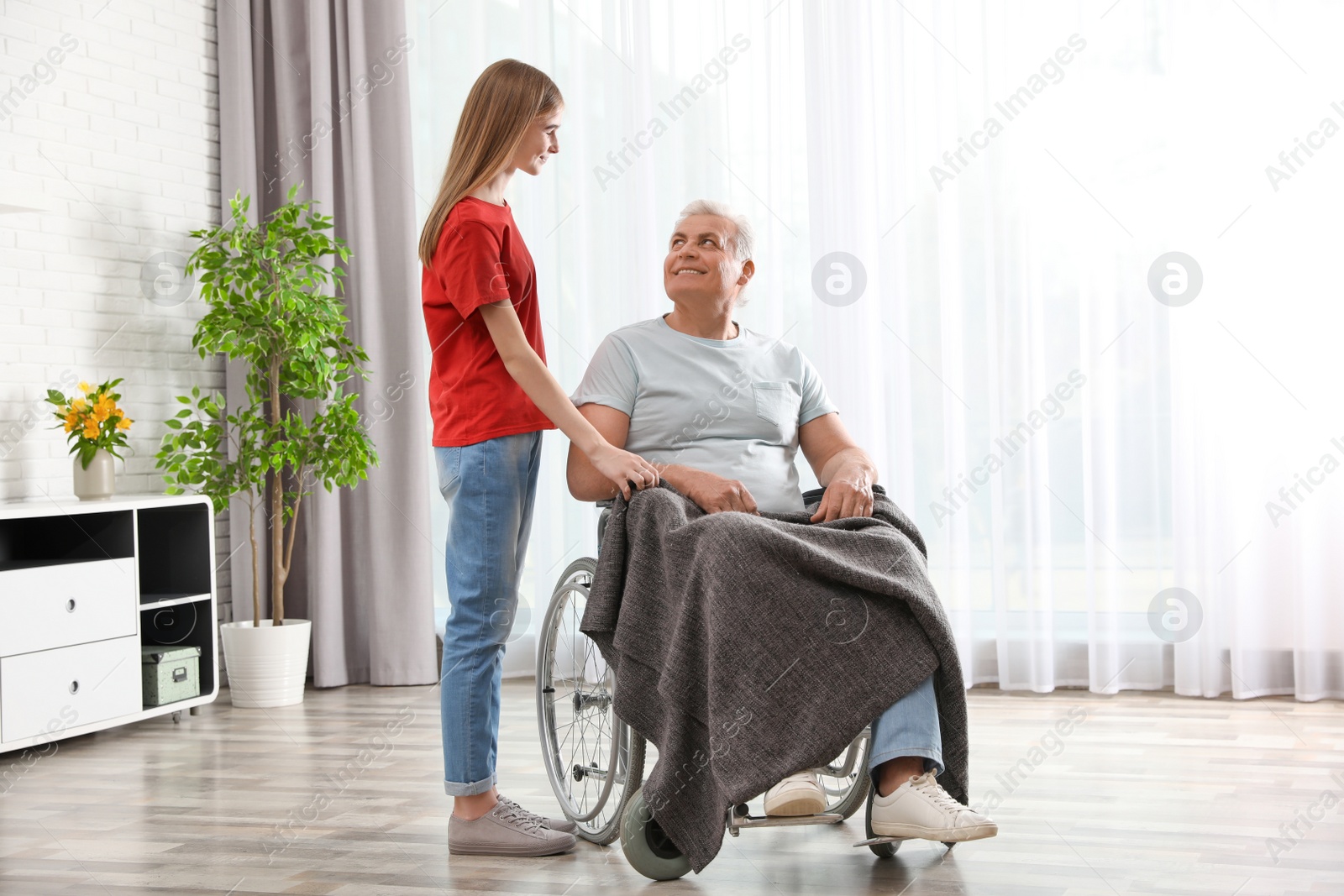 Photo of Teenage girl with grandfather in wheelchair at home