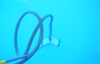 Photo of Cleaning outdoor pool with underwater vacuum, closeup