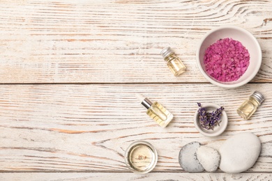 Essential oil, ingredients and space for text on wooden background, flat lay