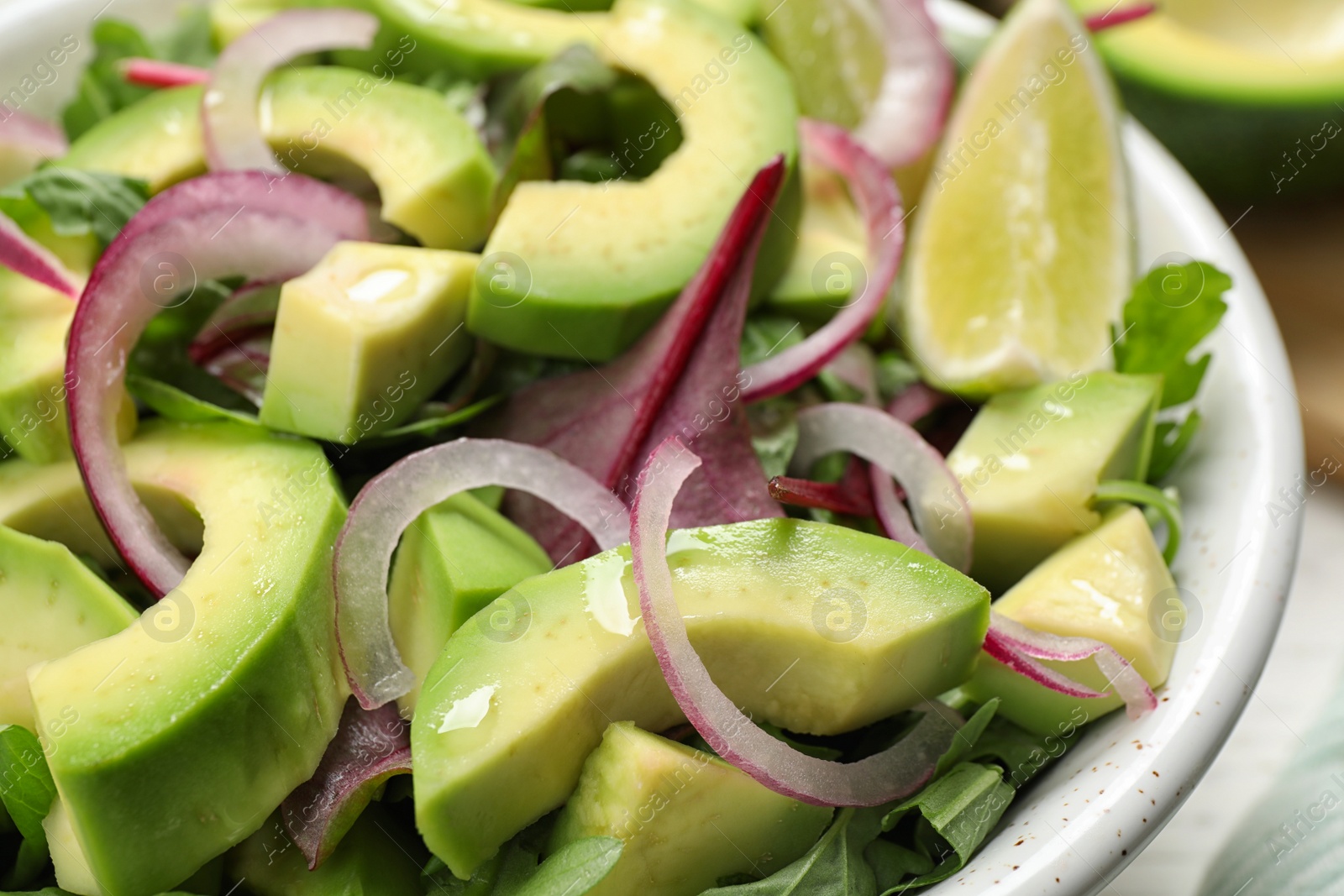 Photo of Delicious avocado salad with arugula in bowl, closeup