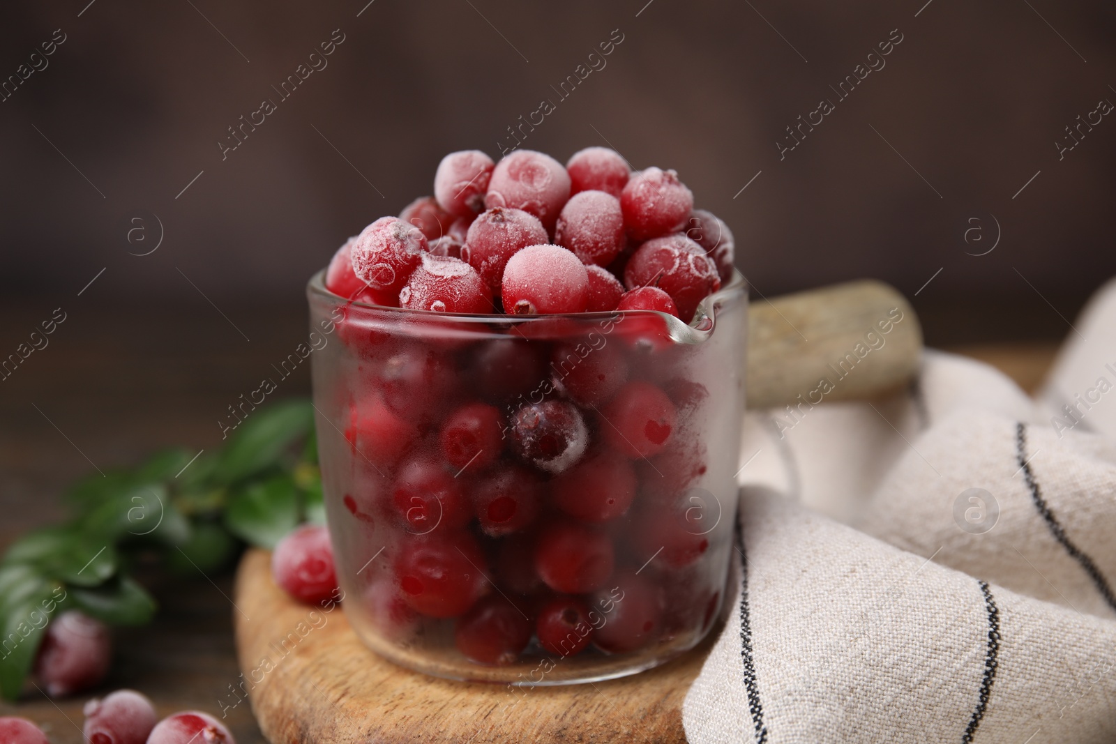 Photo of Frozen red cranberries in glass pot on table, closeup