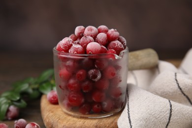 Frozen red cranberries in glass pot on table, closeup