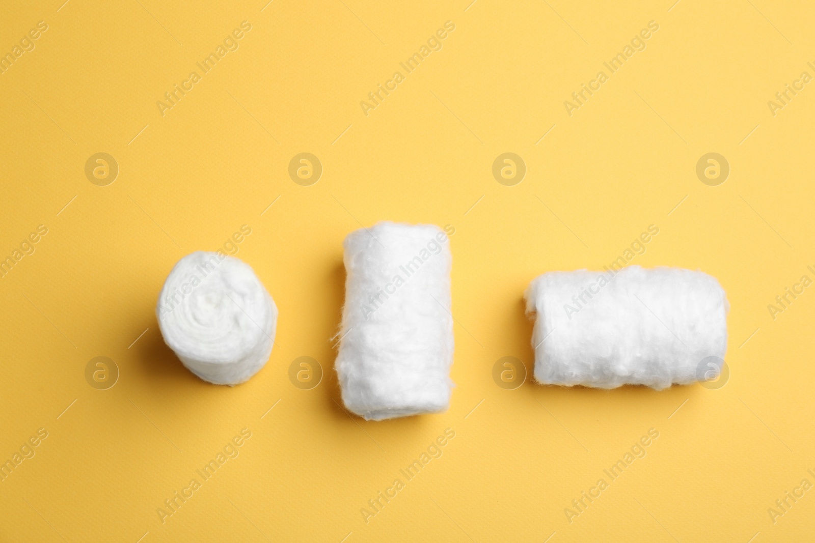 Photo of Three fluffy cotton rolls on color background, flat lay. Space for text