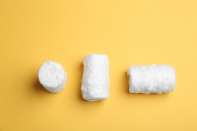 Three fluffy cotton rolls on color background, flat lay. Space for text